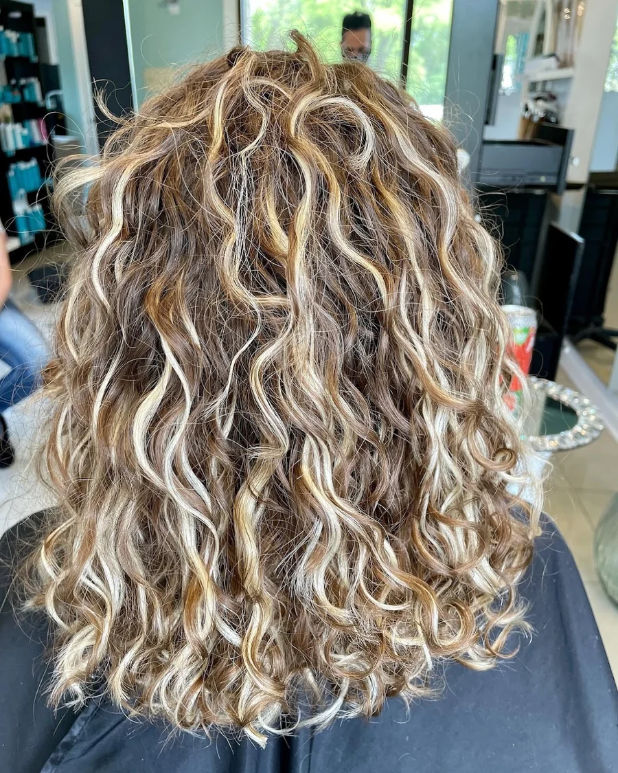Deva cut with blonde balayage highlights on long defined curls, back view by Richie at Damron & Company Salon in Austin