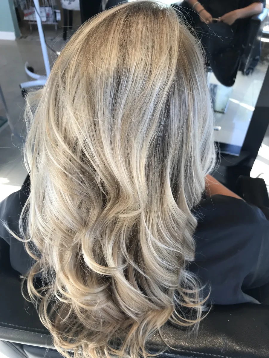 Deva cut with ash-blonde balayage on long waves, back view by Richie at Damron & Company Salon in Austin