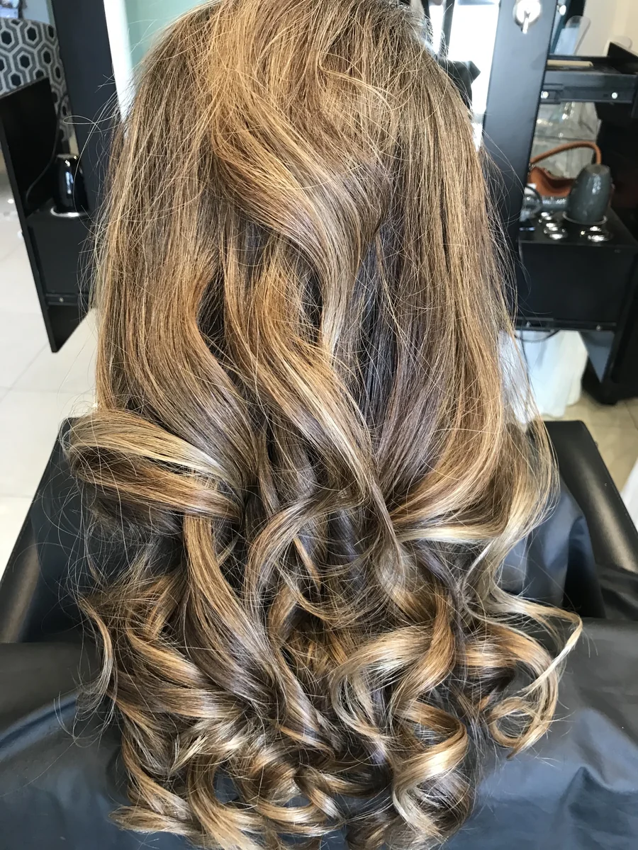 Deva cut with caramel balayage on curled waves, back view by Richie at Damron & Company Salon in Austin