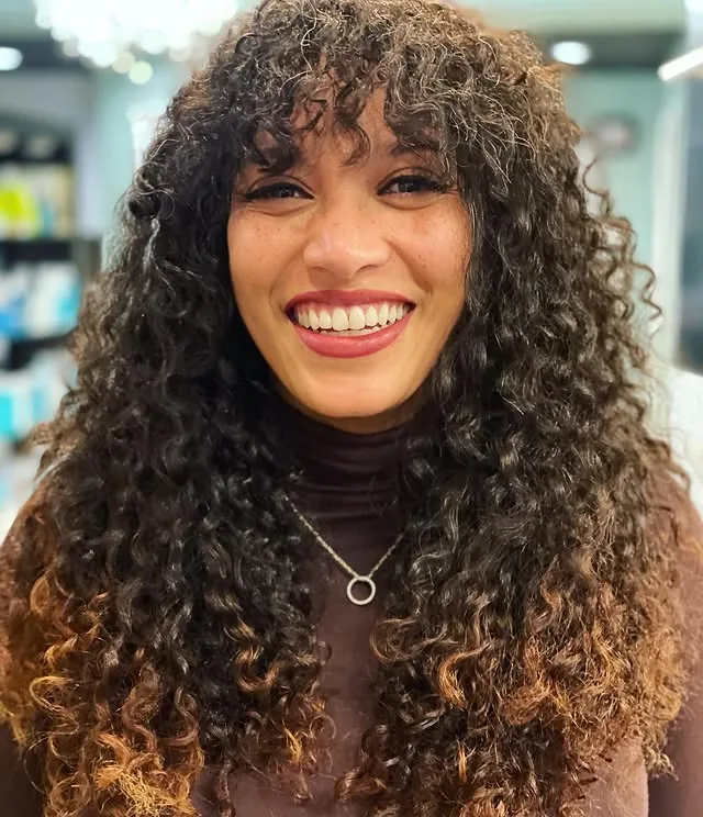 Deva cut with copper color on long dark ringlet curls with curly bangs, laughing client by Richie at Damron & Company Salon in Austin