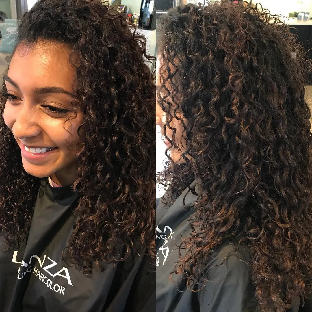 Deva cut with caramel highlights on long dark ringlets, side view, smiling client by Richie at Damron & Company Salon in Austin