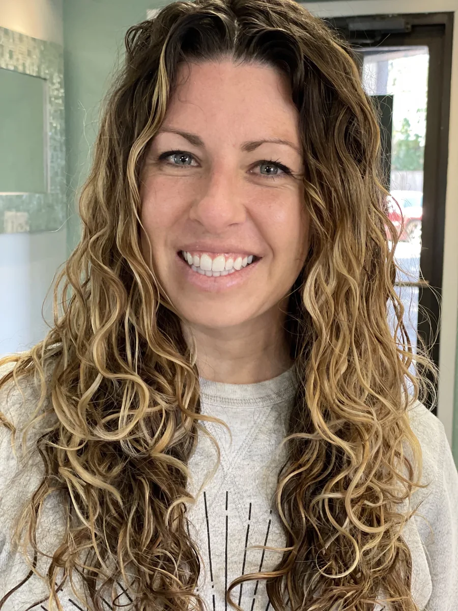 Deva cut with blonde highlights on long waves, smiling client by Richie at Damron & Company Salon in Austin