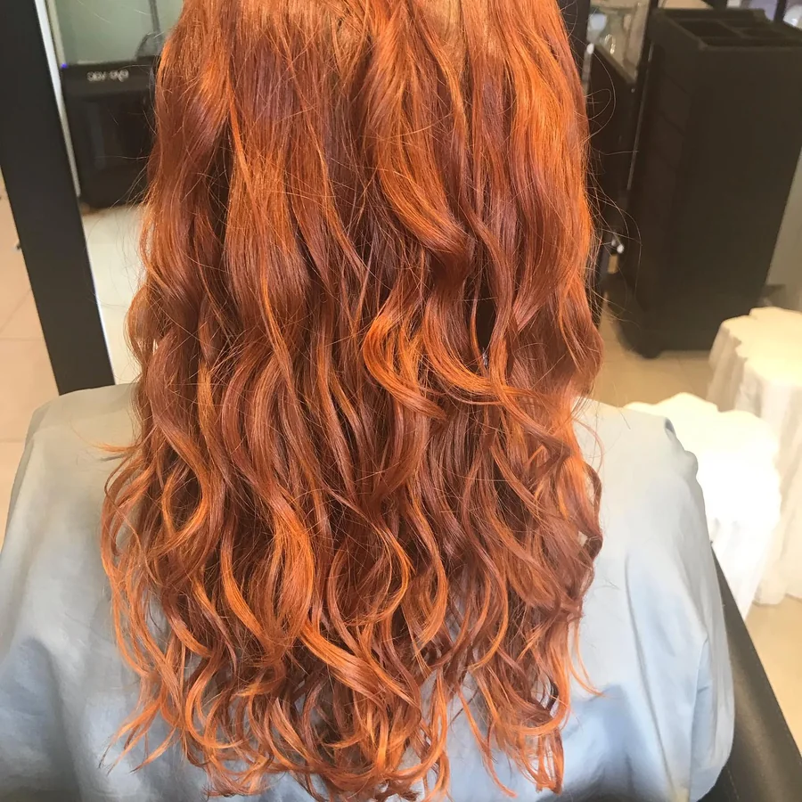Deva cut on long copper-red waves, back view by Richie at Damron & Company Salon in Austin
