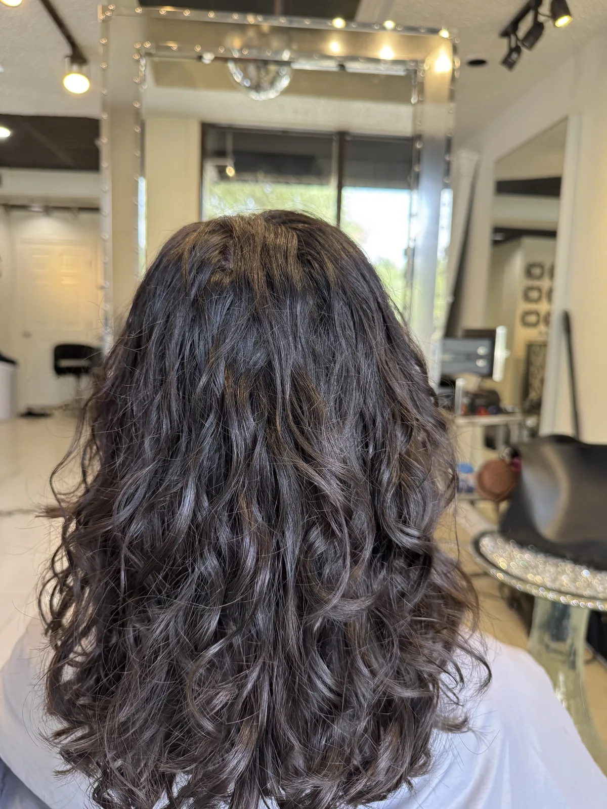 Deva cut on shoulder-length dark waves, back view by Richie at Damron & Company Salon in Austin