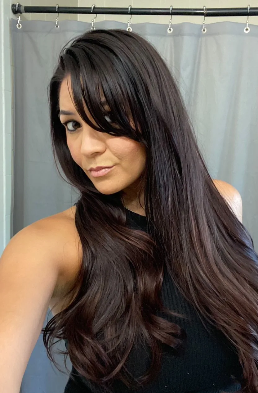Long layered haircut with side-swept bangs on dark smooth hair by Richie at Damron & Company Salon in Austin